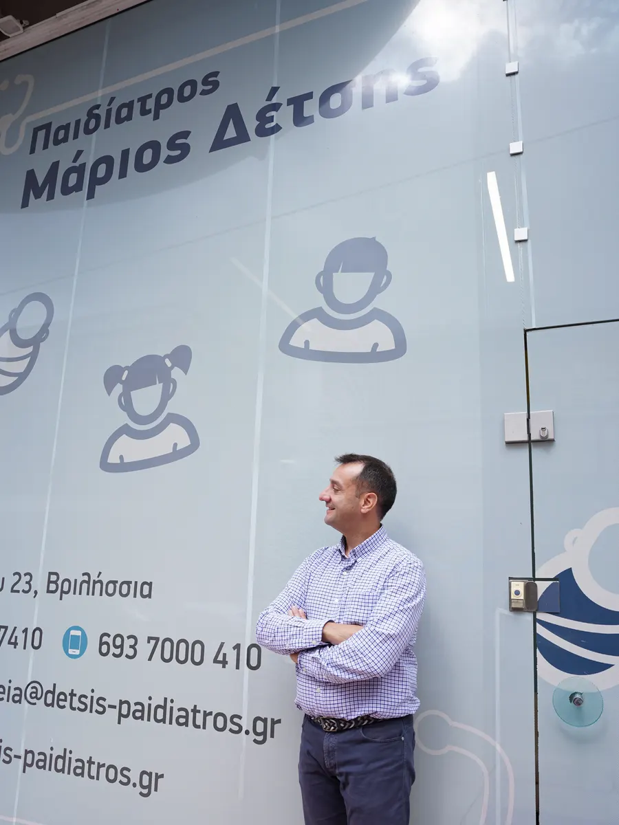 Ο ιατρός Μάριος Δέτσης μπροστά στη βιτρίνα του ιατρείου στα Βριλήσσια